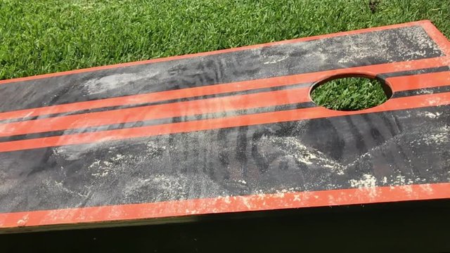 Home made Cornhole backyard game close up with dust cloud flying in air