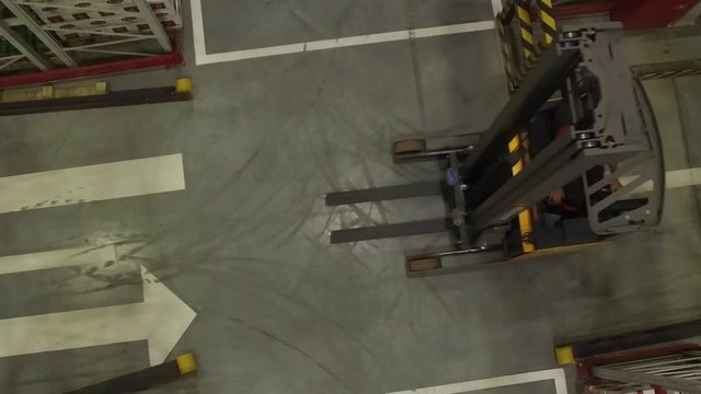 Aerial view of fork lift truck driving in storage warehouse. Logistic, retail industry concept.