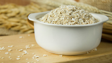 The Healthy breakfast cereal oat flakes in bowl on wooden table.