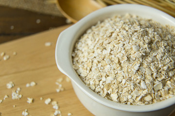 The Healthy breakfast cereal oat flakes in bowl on wooden table.
