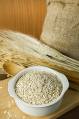 The Healthy breakfast cereal oat flakes in bowl on wooden table.