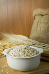 The Healthy breakfast cereal oat flakes in bowl on wooden table.