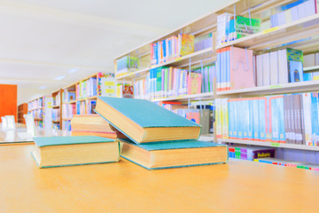 old book red - green. and heap treatise in school library on wooden table.  blurry bookshelves...