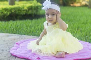 eautiful and white baby, with wreath of flowers, sitting on pink doily on the lawn.  Various expressions and tender emotions.  Yellow dress, brown wicker basket, on spring green grass.