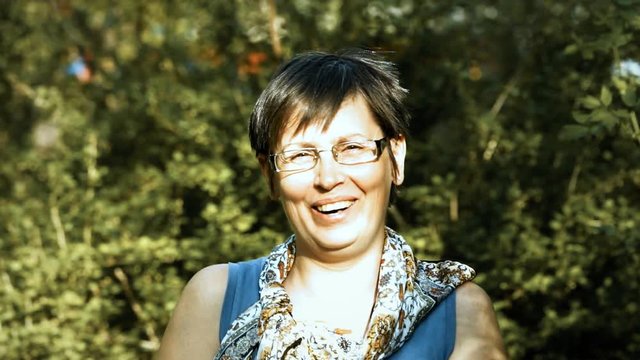 40 year old woman laughing outdoors against the background of foliage