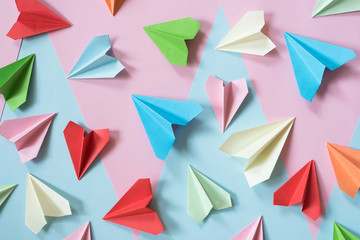 colorful paper airplanes on pastel pink and blue colored background. childhood,freedom and diversity concept