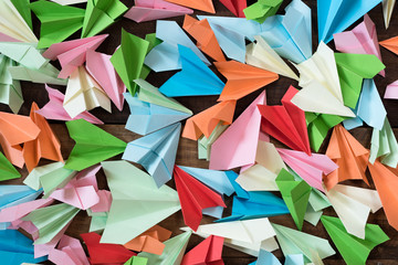 colorful paper airplanes on wooden table background. childhood,freedom,origami and diversity concept
