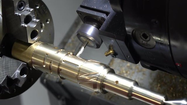 The CNC turning or lathe machine cutting groove slot at the brass shaft by the milling spindle. High technology manufacturing process.
