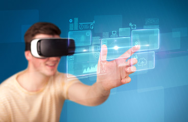 Young impressed man wearing virtual reality goggles with blue squares containing data at his fingers 