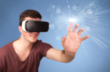 Young impressed man wearing virtual reality goggles with blue hexagons around him 