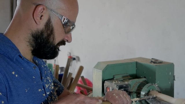 bearded woodworker. carpenter cuts a part on a lathe