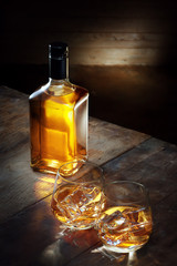 view of glass of  whiskey and a bottle aside on color background. 