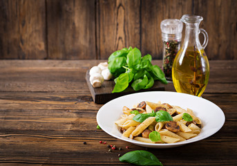 Vegetarian Vegetable pasta penne  with mushrooms  in white bowl on wooden table. Vegan food.
