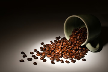 Coffee beans in coffee cup in spotlight on dark background