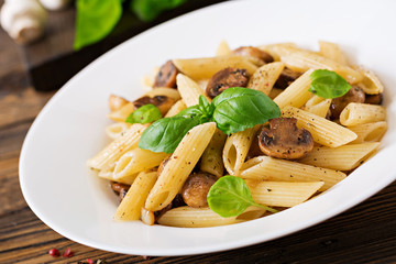 Vegetarian Vegetable pasta penne  with mushrooms  in white bowl on wooden table. Vegan food.