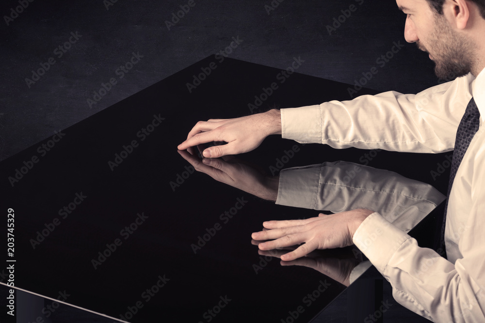 Poster Close up of a hand touching smart table with copy space on black background