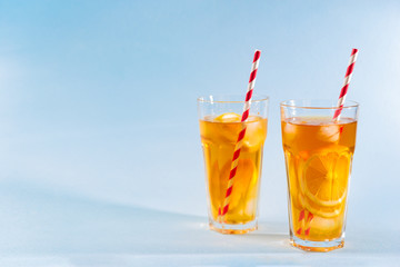 iced tea with lemon in clear glasses on blue background