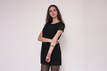 Portrait of a beautiful brunette girl on a gray background in a dress.