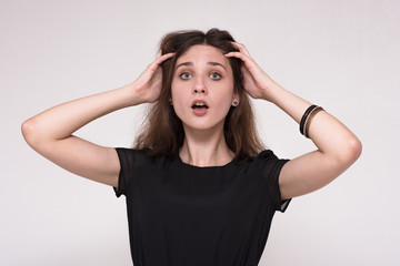 Obraz premium Portrait of a beautiful brunette girl on a gray background showing surprise.
