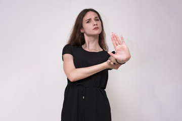 Portrait of a beautiful brunette girl on a gray background showing a denial.