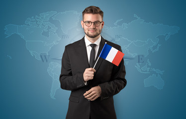 Cheerful businessman standing in front of a map with flag on his hand
