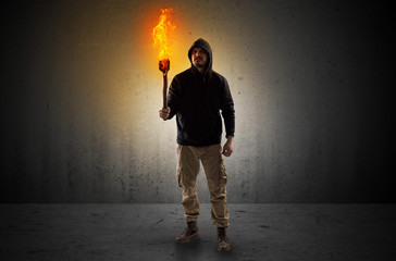 Ugly scary man with burning flambeau walking in an empty space