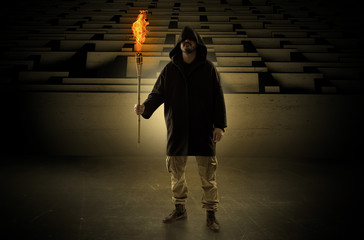 Ugly, aberrant man coming out from the labyrinth with burning flambeau on his hand
