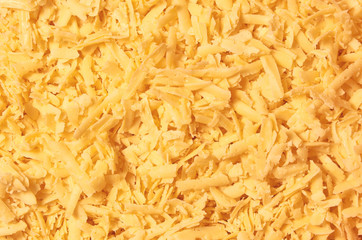 Grated organic milky cheese close up texture background