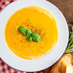 Cream soup with  Pumpkin and Carrot  on Red classic Checkered tablecloth on wooden rustic table. 