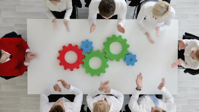 Business problem solution, mechanism of business, teamwork concept, business team sitting around white table with cogs