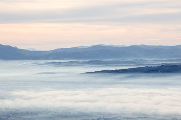 Beautiful aerial view of Umbria valley in a winter morning, with fog covering trees and houses