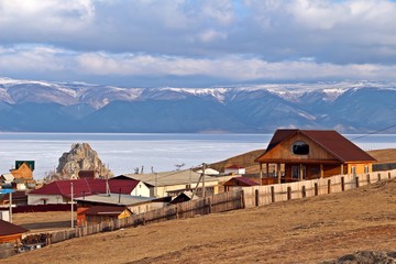 Fototapeta na wymiar Khuzhir city with Shamanka Rock and beautiful mountainious behind Baikal lake in late winter