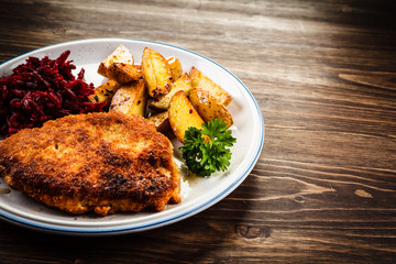 Grilled steak, French fries and vegetables on wooden background