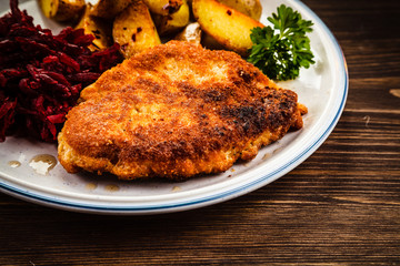 Grilled steak, French fries and vegetables on wooden background