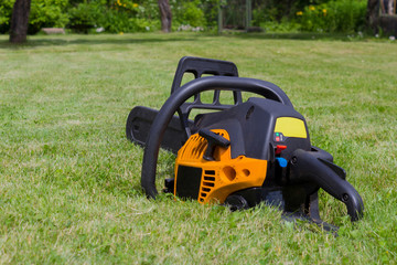 Fototapeta premium Black and orange chainsaw on grass