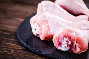 Raw chicken drumsticks on wooden background