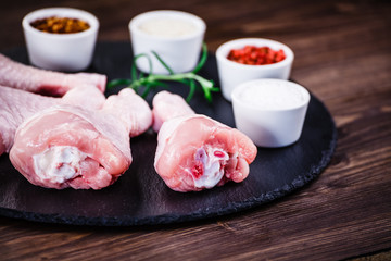 Raw chicken drumsticks on wooden background