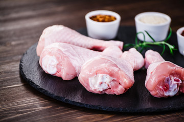 Raw chicken drumsticks on wooden background