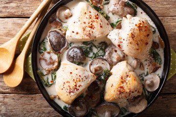 Stewed chicken breast with wild mushroom sauce and spinach closeup on a plate. horizontal top view
