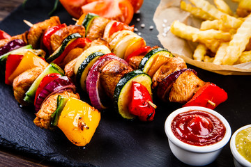 Kebabs - grilled meat with french fries and vegetables on wooden background