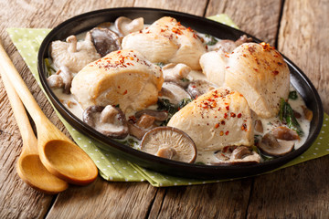 Spicy chicken fillet with a mix of wild mushrooms and spinach in a creamy sauce close-up on a plate. horizontal