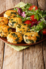 Fried meat balls with spinach and a salad of fresh vegetables close-up on a plate. vertical