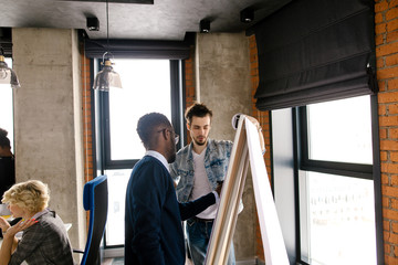 closeup image of afro businessman putting his ideas on the board with flipping sheet . white scheme on the flipchart while business meeting