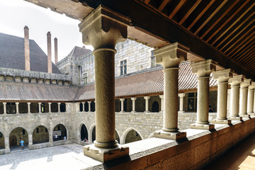 view of the main courtyard of the palace of the Dukes of Braganza from the arcaded gallery on the first floor and with tourists visiting it, large stone chimneys, r