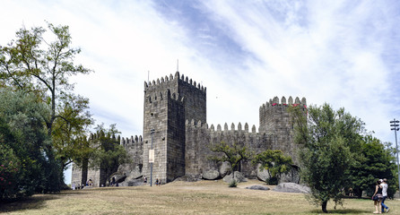 Fototapeta na wymiar Guimaraes, Portugal. August 14, 2017: exterior of the royal stone castle built in the 11th century by the king of Portugal named Afonso Henriques, with ramparts and fortified battlements