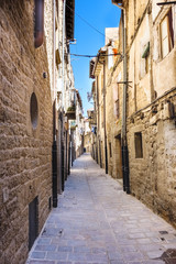 Fototapeta na wymiar Narrow alley with floor of stone slabs and old houses of stone facades and iron balconies, typical of the north of Spain in the old part of the town called Laguardia in Alava (Spain)