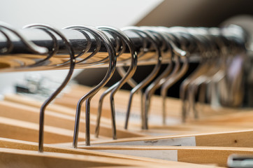 Wooden clothes hangers in a row hanging on the rail