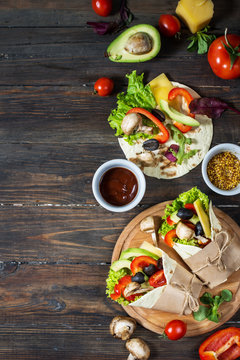 Healthy vegan lunch snack. Tortilla wraps with mushrooms, fresh vegetables and Ingredients on wooden background.