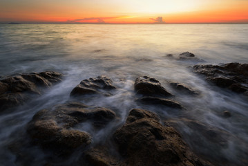 wave at the sea on the rock with sunset sky