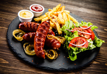 Grilled sausages, French fries and vegetables